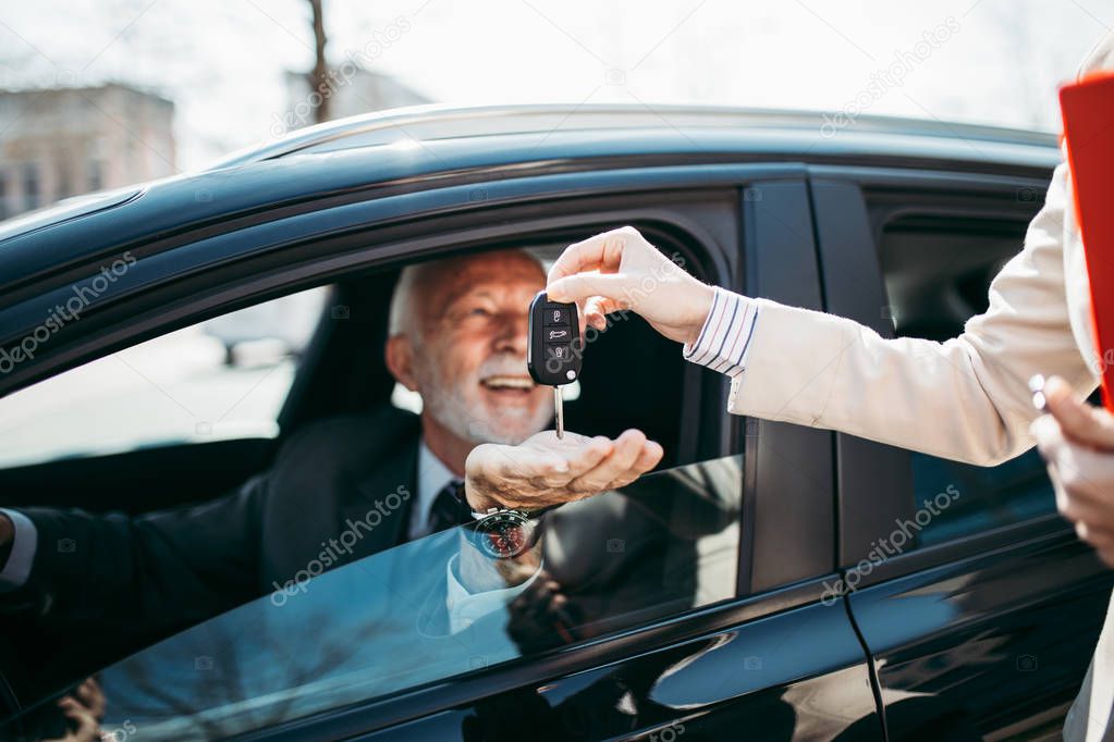 Young woman car dealer gives the keys to the new owner. Hands with keys close up.