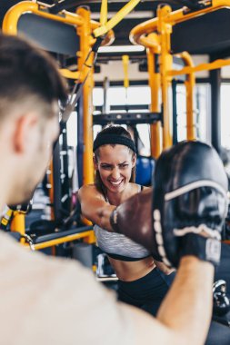 Kickboks eğitim eğitmen ile genç çekici kadın. Büyük sarı boks çantasına vurdu ya da yumrukluyor..