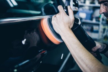 Araba tamiri, oto tamirhanesinde orbital parlatıcıyla el işi. Seçici odak.