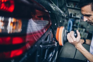 Araba tamiri, oto tamirhanesinde orbital parlatıcıyla el işi. Seçici odak.