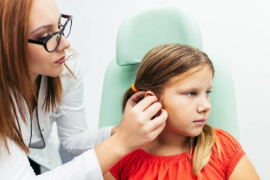 Young girl at medical examination or hearing aid checkup in otolaryngologist's office