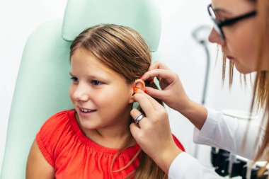 Young girl at medical examination or hearing aid checkup in otolaryngologist's office