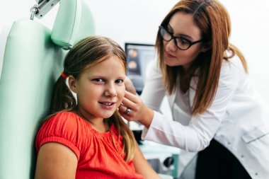 Young girl at medical examination or hearing aid checkup in otolaryngologist's office