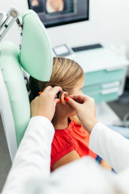 Young girl at medical examination or hearing aid checkup in otolaryngologist's office