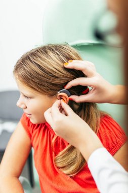 Young girl at medical examination or hearing aid checkup in otolaryngologist's office