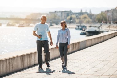 Formda koşan ve genç yetişkin kız koçu ya da eğitmeniyle birlikte egzersiz yapan formda kıdemli bir adam..