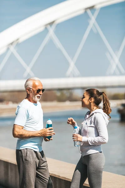 Fit senior man in good shape jogging and exercising together with his young adult daughter coach or instructor.