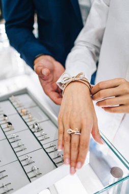 Modern kuyumcuda alışveriş yapan güzel bir çift. Pahalı bir yüzük ve bilezik takmış bir kadının elini yakın plan çek..