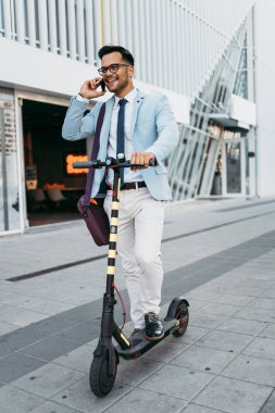 Şehir caddesinde elektrikli scooter kullanan ve kullanan genç modern bir adam. Modern ve ekolojik ulaşım kavramı.