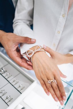 Modern kuyumcuda alışveriş yapan güzel bir çift. Pahalı bir yüzük ve bilezik takmış bir kadının elini yakın plan çek..