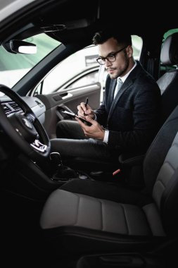 Galeride çalışan araba satıcısı ve araba detaylarını son kez kontrol ediyor alıcı gelmeden önce..