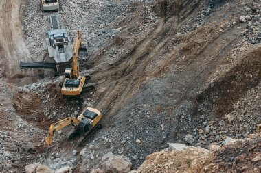 Heavy machinery excavators working on quarry and loading stone and granite into dump trucks. Bird eye perspective photo. clipart