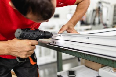 Elle çalışan işçi PVC kapı ve pencereleri birleştiriyor. İmalat işleri. Seçici odaklanma. Alüminyum ve PVC pencere ve kapı üretim fabrikası.