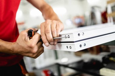 Elle çalışan işçi PVC kapı ve pencereleri birleştiriyor. İmalat işleri. Seçici odaklanma. Alüminyum ve PVC pencere ve kapı üretim fabrikası.