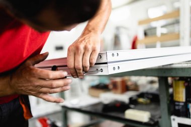 Elle çalışan işçi PVC kapı ve pencereleri birleştiriyor. İmalat işleri. Seçici odaklanma. Alüminyum ve PVC pencere ve kapı üretim fabrikası.