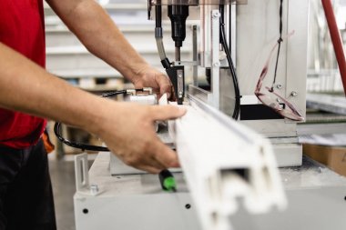 Elle çalışan işçi PVC kapı ve pencereleri birleştiriyor. İmalat işleri. Seçici odaklanma. Alüminyum ve PVC pencere ve kapı üretim fabrikası.