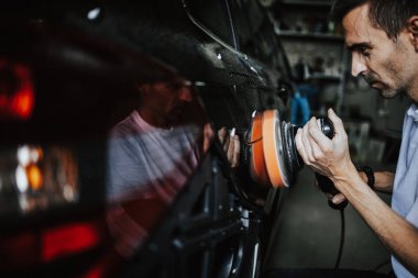Araba tamiri, oto tamirhanesinde orbital parlatıcıyla el işi. Seçici odak.