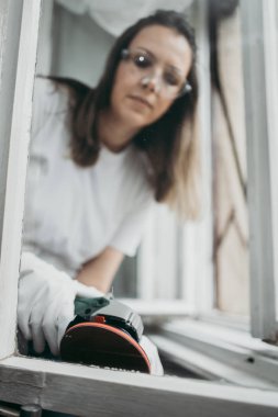 Güzel ve çalışkan orta yaşlı bir kadın eski evini ya da dairesini yeniliyor. O, profesyonel öğütücü tutuyor ve daha sonra resim yapmak için eski pencereleri temizliyor. Ev işi konseptini kendin yap..