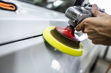 Araba detaylandırma - Oto tamir atölyesinde orbital parlatıcı ile Eller. Yakın çekim. Seçici odaklama.