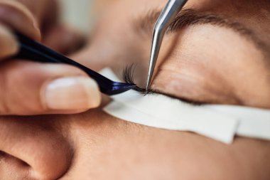 Kirpik uzatma işleminde güzel orta yaş kadın. Kozmetik ve vücut bakımı yakın çekim.