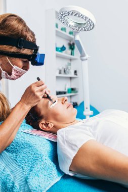 Kirpik uzatma işleminde güzel orta yaş kadın. Kozmetik ve vücut bakımı yakın çekim.