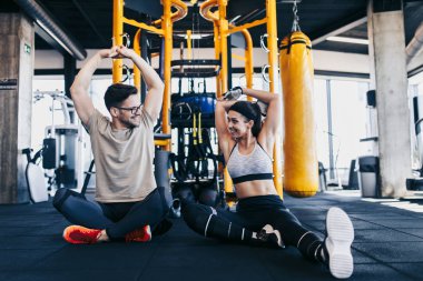 Modern spor salonunda spor yapan genç ve çekici bir kadın. Kişisel fitness hocası veya koçuyla birlikte..