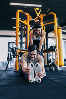 Modern spor salonunda spor yapan genç ve çekici bir kadın. Kişisel fitness hocası veya koçuyla birlikte..