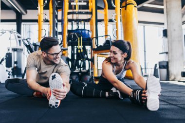 Modern spor salonunda spor yapan genç ve çekici bir kadın. Kişisel fitness hocası veya koçuyla birlikte..