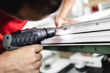 Elle çalışan işçi PVC kapı ve pencereleri birleştiriyor. İmalat işleri. Seçici odaklanma. Alüminyum ve PVC pencere ve kapı üretim fabrikası.