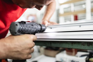 Elle çalışan işçi PVC kapı ve pencereleri birleştiriyor. İmalat işleri. Seçici odaklanma. Alüminyum ve PVC pencere ve kapı üretim fabrikası.