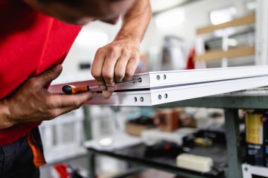 Elle çalışan işçi PVC kapı ve pencereleri birleştiriyor. İmalat işleri. Seçici odaklanma. Alüminyum ve PVC pencere ve kapı üretim fabrikası.