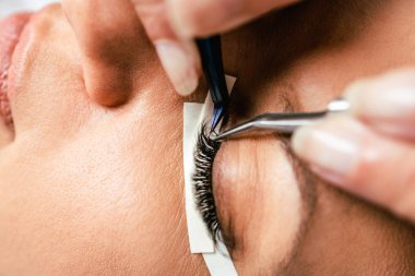 Kirpik uzatma işleminde güzel orta yaş kadın. Kozmetik ve vücut bakımı yakın çekim.