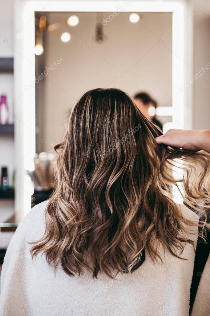 Beautiful brunette woman with long hair at the beauty salon getting a hair blowing. Hair salon styling concept.