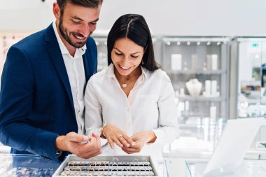 Modern kuyumcuda alışveriş yapan güzel bir çift. Pahalı bir yüzük ve bilezik takmış bir kadının elini yakın plan çek..