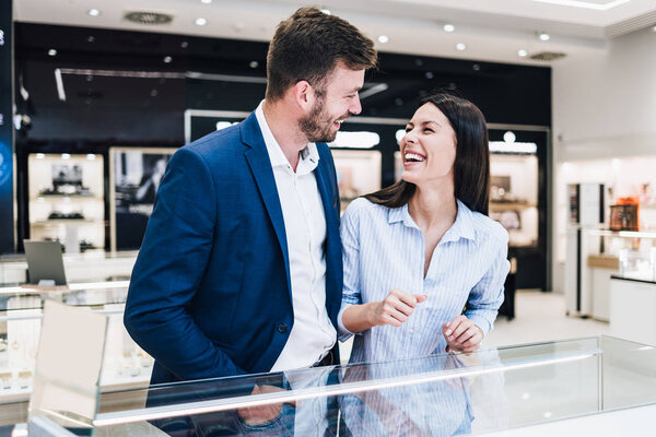 Beautiful couple enjoying in shopping at modern jewelry store. 