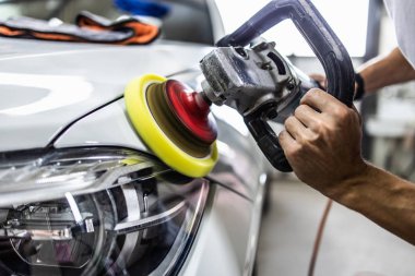 Araba tamiri, oto tamirhanesinde orbital parlatıcıyla el işi. Seçici odak.