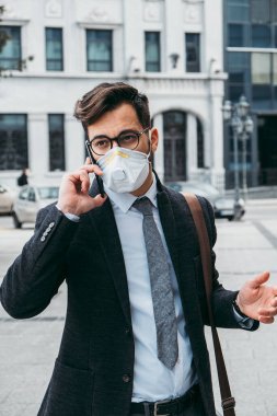 Şehir caddesinde telefon kullanan koruyucu maskeli bir iş adamı. Virüs salgını veya salgın hastalık konsepti.