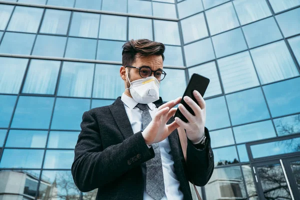 Business man with protective face mask using phone on city street. Virus pandemic or epidemic concept.