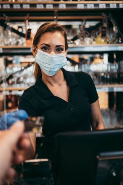 Modern bir süpermarkette ya da markette kasiyerlik yapan güzel ve pozitif kadın kasiyer. Salgın ya da salgın yaşam tarzı ve tüketim kavramı.