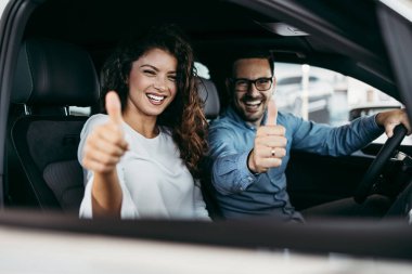 Mutlu orta yaşlı çift galeride yeni araba seçerken ve alırken eğleniyor..