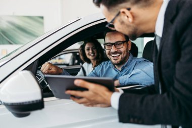 Araba galerisinden araba alan orta yaşlı bir çift. Araba satıcısı doğru karar vermelerine yardımcı oluyor..