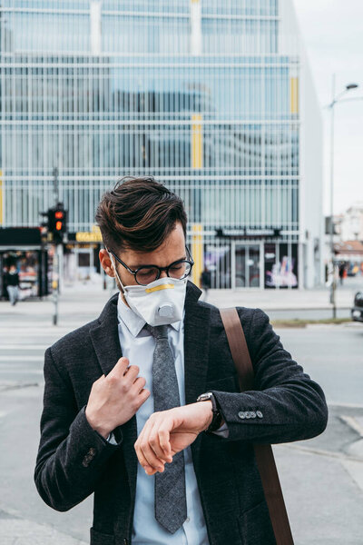 Business man standing or walking on city street with protective face mask. Virus epidemic concept.