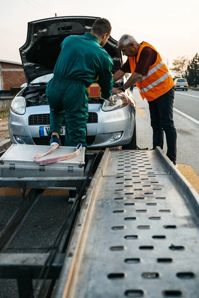 两名从事拖轮服务的道路助理试图启动装有起跳装置的汽车发动机和配备空压机的能源站 路边援助概念 — 图库照片