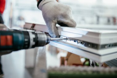 Elle çalışan işçi PVC kapı ve pencereleri birleştiriyor. İmalat işleri. Seçici odaklanma. Alüminyum ve PVC pencere ve kapı üretim fabrikası.