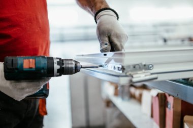 Elle çalışan işçi PVC kapı ve pencereleri birleştiriyor. İmalat işleri. Seçici odaklanma. Alüminyum ve PVC pencere ve kapı üretim fabrikası.