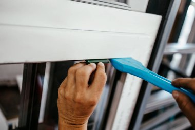 Elle çalışan işçi PVC kapı ve pencereleri birleştiriyor. İmalat işleri. Seçici odaklanma. Alüminyum ve PVC pencere ve kapı üretim fabrikası.