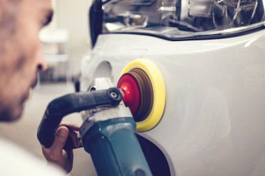 Araba tamiri, oto tamirhanesinde orbital parlatıcıyla el işi. Seçici odak.