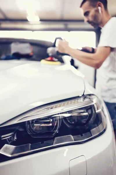 Car detailing - Hands with orbital polisher in auto repair shop. Selective focus.