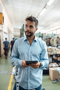 Orta yaşlı işadamı endüstriyel üretimde kalite kontrol yapıyor. Elektrik konutlarının endüstriyel üretim fabrikası ve artan tutuklamalar.