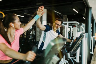 Spor salonunda bisiklet süren genç ve çekici bir kadın ve erkek. Bisiklet sürerken bacak egzersizi ve kardiyo egzersizi yapıyorlar..